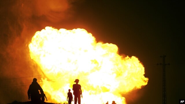 Egyptian Bedouins watch as smoke and flames rise into the air after masked gunmen blew up a terminal of the Egyptian natural gas pipeline to Israel and Jordan in el-Arish, in the northern part of Egypt's Sinai Peninsula, July 12, 2011