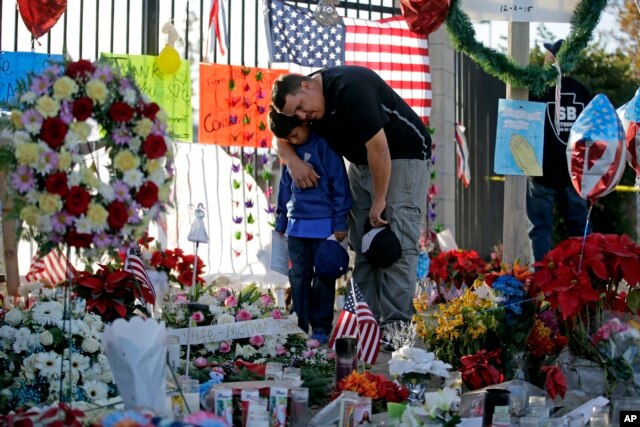 FILE - Gary Mendoza, and his son Michael pay their respects at a makeshift memorial site honoring shooting victims, in San Bernardino, Calif., Dec. 7, 2015.