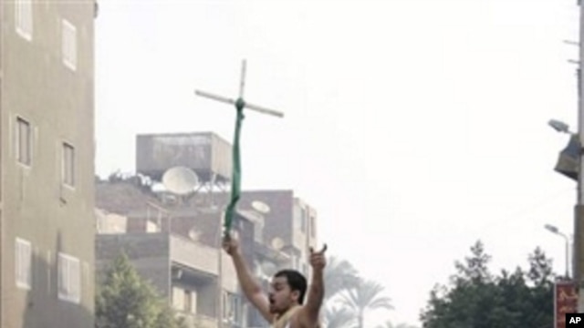Angry Egyptian Christians smash a police vehicle as they raise a cross during a riot, which left one one person dead, after authorities halted construction on a church saying the local Christian community had violated a building permit, in Cairo, Egypt, W