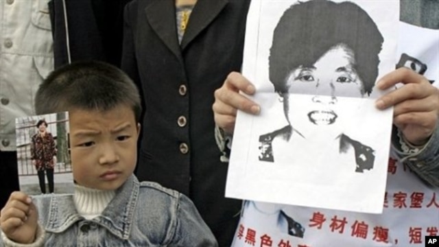 A young boy holds up a photo of his mother as he joins family members wearing posters describing the woman as missing from her home in Xian, northern China's Shaanxi province, as they launch a campaign to locate her (File Photo).