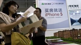 A real estate agent explains property development details to a woman during the China Property and Investment Show in Beijing, September 21, 2012.