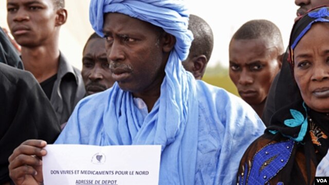 People in the Malian capital, Bamako, hold signs with information about where to drop donations for communities affected by unrest in the north. 8 April 2012. 