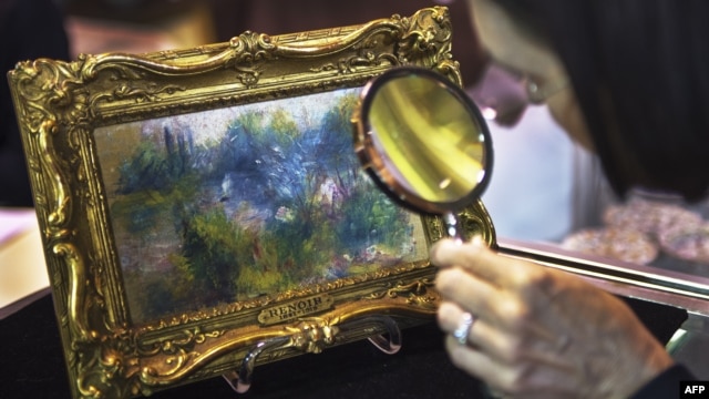 An art shopper looks closely at a 5.5 inch by 6.6 inch painting by French Impressionist master Pierre-Auguste Renoir in Alexandria, Virginia, September 25, 2012. 