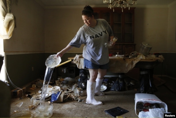 Marilyn Mays drains water from dishes in the dining room of her mother's home after heavy rains led to flooding in Denham Springs, Louisiana, Aug. 17, 2016.