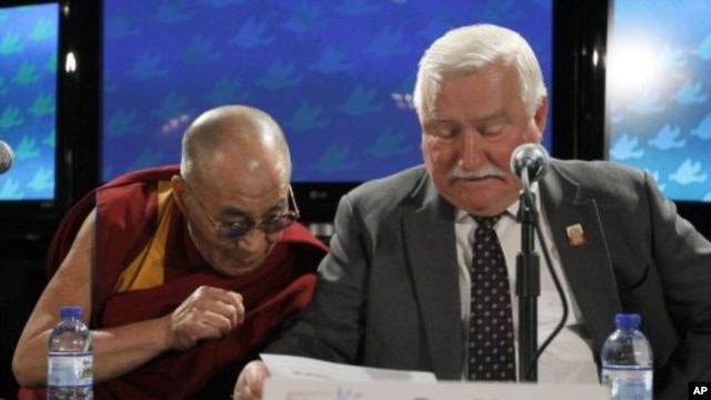 The Dalai Lama, right, looks at the remarks of Lech Walesa, former president of the Republic of Poland, during a news conference after the final session of the World Summit of Nobel Peace Laureates, Chicago, April 25, 2012.