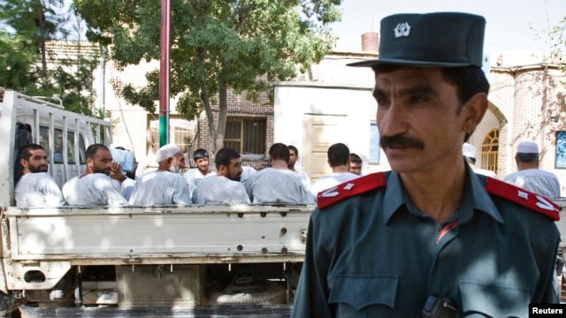 An Afghan police officer stands guard in front of a truck carrying Afghan prisoners on their way to court in Herat, western Afghanistan, August 16, 2009.