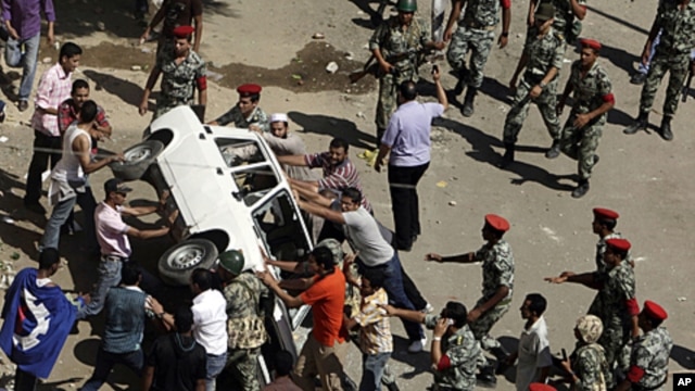 Protesters and military police tussle over trying to overturn a police car after protesters broke the windows in front of the court complex in Suez, Egypt, July 6, 2011