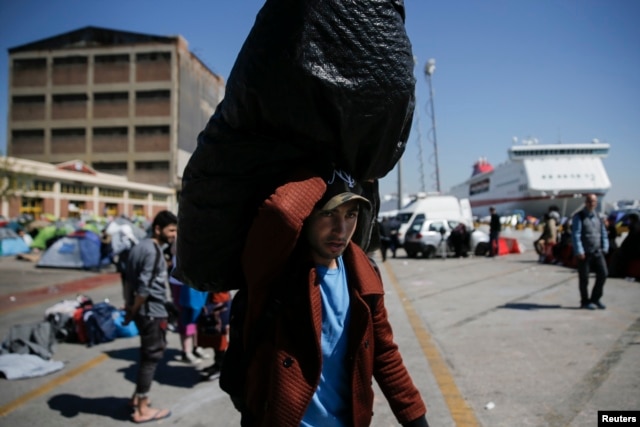 A refugee carries his belongings before boarding a bus heading to other parts of the country where refugees and migrants will be accommodated, at the port of Piraeus, near Athens, Greece, March 31, 2016.