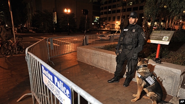 A police officer and dog guard stand behind barricades after police arrested people sleeping in an expansion of the Occupy Boston tent village on the Rose Kennedy Greenway in Boston, in the early morning hours, October 11, 2011.
