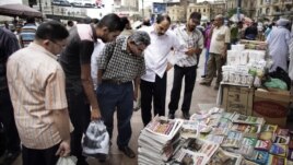 Egyptians look at newspapers displayed at a kiosk outside the Al-Fatah Mosque in Cairo, May 25, 2012. 