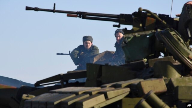 FILE- separatistas apoiados pelos russos sentar em cima de um tanque em um posto de controle ao norte de Luhansk, leste da Ucrânia, 14 de janeiro de 2015.