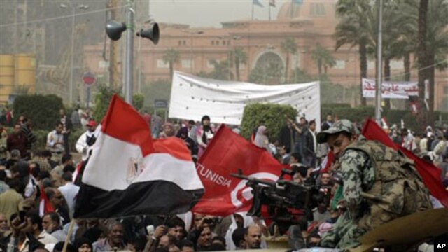 An Egyptian army soldier watches thousands of Egyptian gather at Tahrir Square, the focal point of the Egyptian uprising, flashing Egyptian and Tunisan flags in Cairo, February 25, 2011