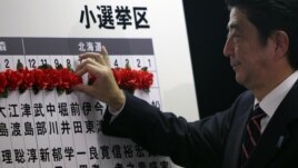Japan's main opposition leader Shinzo Abe of the Liberal Democratic Party (LDP) marks on the name of one of those elected in parliamentary elections at the party headquarters in Tokyo, December 16, 2012. 