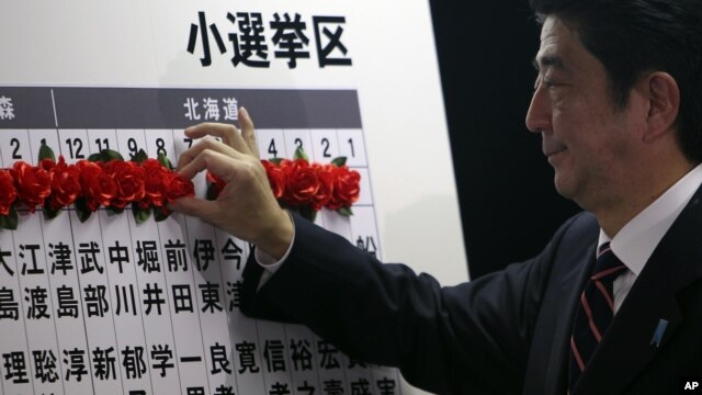 Japan's main opposition leader Shinzo Abe of the Liberal Democratic Party (LDP) marks on the name of one of those elected in parliamentary elections at the party headquarters in Tokyo, December 16, 2012. 