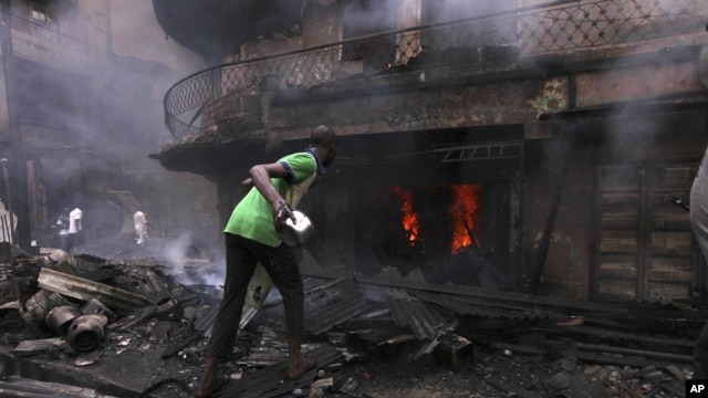 Un homme essayant de contenir l'incendie d'une maison et un entrepot a Lagos Island, Lagos, Nigeria, December 26, 2012.