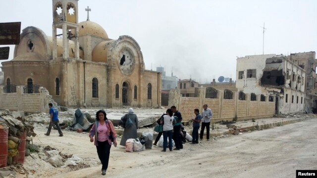 Warga berjalan di defat gereja di wilayah Qusair yang hancur di Suriah, 8 Juni 2013 (Foto: dok). Kelompok oposisi utama Suriah menuduh pasukan pemerintah menempatkan senjata berat di Biara Cherubim, biara ortodoks bersejarah di utara Damaskus.