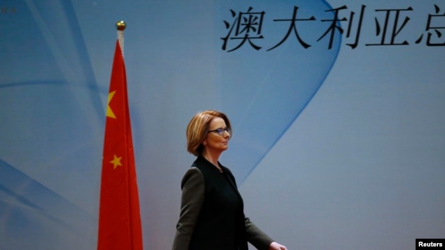 Thủ tướng Australia Julia Gillard đi ngang quốc kỳ của Trung Quốc khi bà đến dự bữa ăn trưa của Diễn đàn Kinh tế và Thương mại Trung Quốc-Australia tại một khách sạn ở Bắc Kinh, ngày 9/4/2013. 