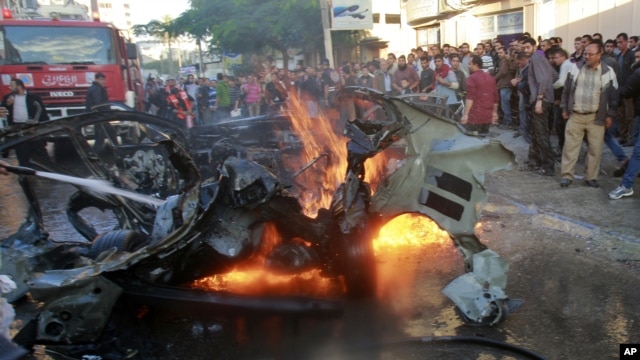 Warga Palestina di kota Gaza berkerumun di dekat mobil yang ditumpangi komandan Hamas, Ahmed al-Jaabari yang hancur akibat serangan udara Israel (14/11).  
