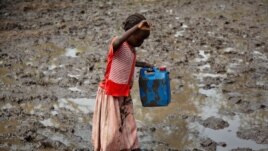 A girl walks through mud to get water at the Yusuf Batil refugee camp in Upper Nile, South Sudan, July 4, 2012.