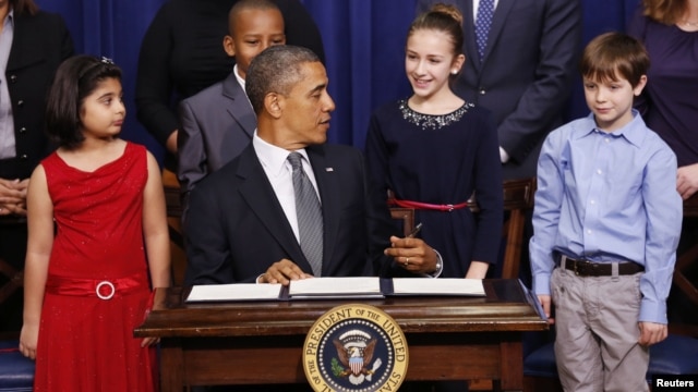 President Barack Obama talks with 11-year-old letter writer Julia Stokes (2nd R in blue dress) as he signs executive orders on gun violence during an event at the White House, January 16, 2013.