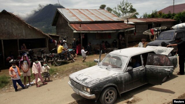 Warga desa berdiri di dekat mobil yang diselimuti debu, menunggu untuk dievakuasi, sementara gunung Sinabung di Karo, Sumatera Utara terus mengeluarkan debu dan lava panas(15/9).