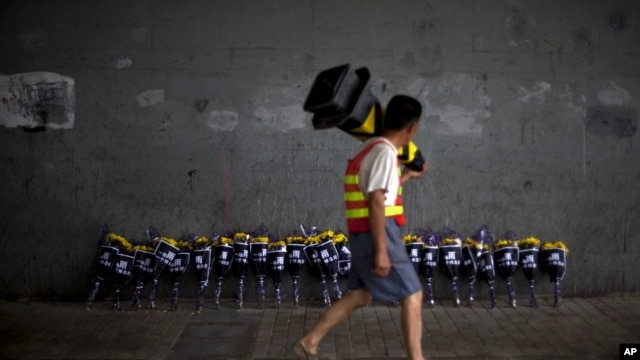 A road worker walks past flowers placed under a bridge where a man drowned July 21 in his flooded car on a main road in Beijing, July 27, 2012. 