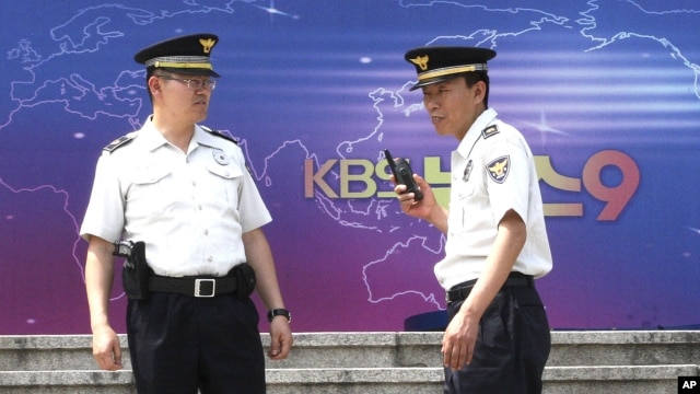 South Korean police officers stand guard in front of the Korea Broadcasting System (KBS) building in Seoul, South Korea, June 4, 2012. 