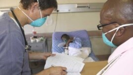 A doctor (left) and a nurse discuss the condition of a patient infected with both HIV and tuberculosis in a hospital in South Africa  