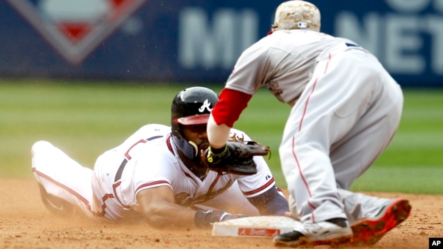 Jason Heyward of Atlanta, left, tries to touch the base before being tagged out by Dustin Pedroia at a baseball game on May 26, 2014.