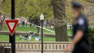 Un policía observa en el fondo el girocóptero que aterrizó en el jardín Oeste del Capitolio.