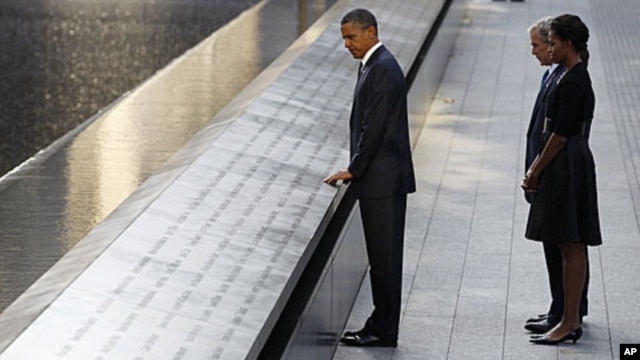 President Barack Obama touches the names of victims engraved on the side of the north pool of the World Trade Center site as former President George W. Bush, first lady Michelle Obama and former first lady Laura Bush (obscured) look on during ceremonies m