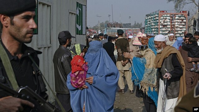 A policeman looks on as passengers wait to cross the Pakistan-Afghanistan border on foot in the northwest town of Torkham, November 27, 2011.