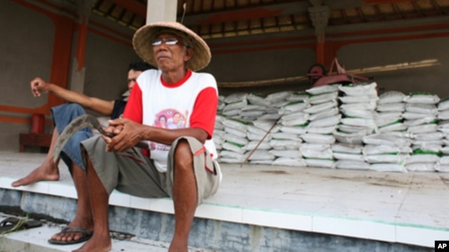 Farmers in Indonesia sitting in front of processed rice that is ready to be sold. Economists say rice farmers living below the poverty line could be the most vulnerable to the impact of floods in Southeast Asia.