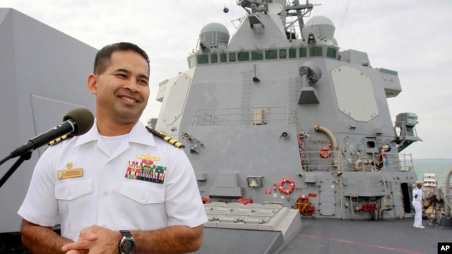 In this photo taken Dec. 3, 2010, U.S. navy officer Michael "Vannak Khem" Misiewicz smiles as he delivers his welcome speech on the deck of the U.S. Navy destroyer USS Mustin at Cambodian coastal international see port of Sihanoukville, about  220 kilometers (137 miles) southwest of Phnom Penh, Cambodia. Misiewicz finally returned home Friday as commander of the U.S. Navy destroyer USS Mustin, reuniting with the relatives who wondered whether they would ever see him alive, and the aunt who helped arrange his adoption. His ship departs Monday. (AP Photo/Heng Sinith)