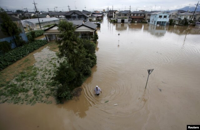 A man wades through a residential area flooded by the Kinugawa river, caused by typhoon Etau, in Joso, Ibaraki prefecture, Japan, September 10, 2015.