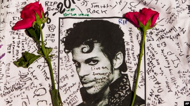 Những bông hoa đặt trên áo thun có chữ ký của các fan hâm mộ huyền thoại âm nhạc Prince ở nơi tưởng niệm tạm thời bên ngoài nhà hát Apollo ở New York, thứ Sáu ngày 22 tháng 4 năm 2016.