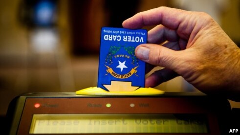 A poll worker inserts an electronic voting card into a machine in Sparks, Nevada, Nov. 6, 2012.