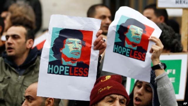 Demonstrators hold up posters depicting Libya's Moammar Gadhafi during a protest in Brussels, February 25, 2011