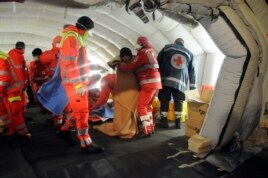 Medics help migrants in a tent after they arrived onboard the Blue Sky M cargo ship at the Gallipoli harbor, southern Italy, Dec. 31, 2014.
