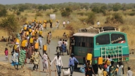 Internally displaced people carry water from outside as they walk toward the entrance of a United Nations Mission in the Republic of South Sudan base in Malakal, Feb. 6, 2014.