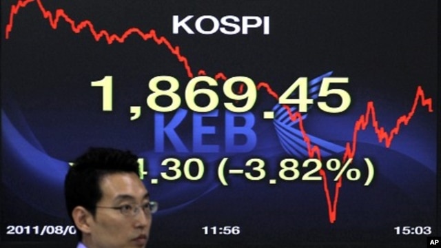 A foreign currency dealer of the Korea Exchange Bank walks past a screen displaying the Korea Composite Stock Price Index (KOSPI) at the bank's dealing room in Seoul August 8, 2011.