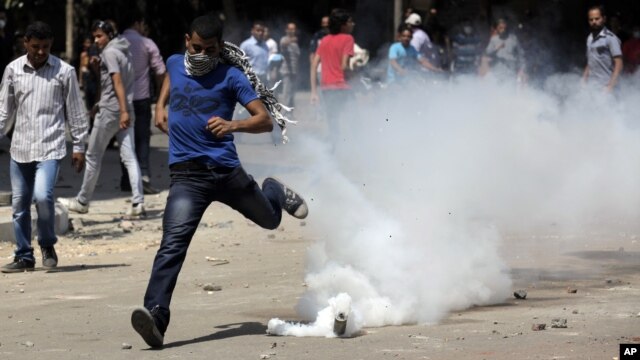 An Egyptian protester runs away from a tear gas canister fired by riot police, near street leading to US embassy during clashes in Cairo, Egypt, Sept 14, 2012.