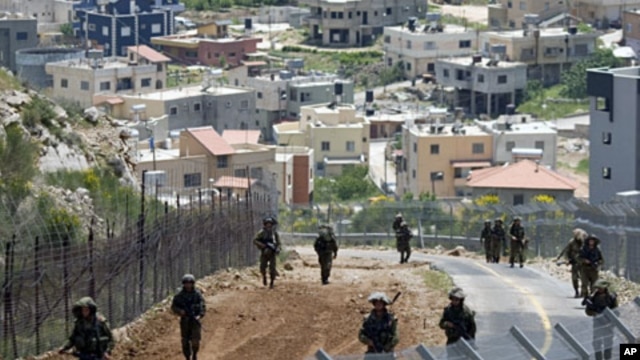 With the Druze village of Majdal Shams in the background, Israeli troops patrol along the border between Israel and Syria the Golan Heights, May 20, 2011