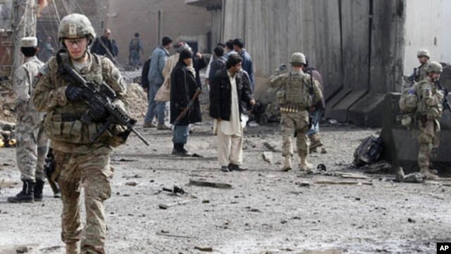 U.S. soldiers and Afghan policemen keep watch after a car bomb blast in the southern city of Kandahar, Afghanistan, February 20, 2012.