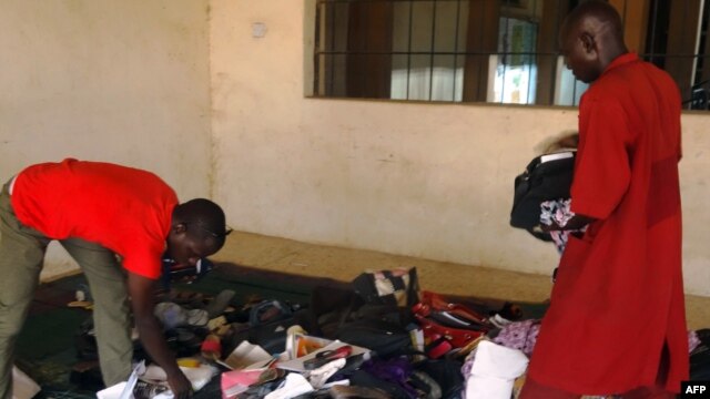 A student aided by a porter rummages through personal effects abandoned by students at the Federal College of Education in the northern Nigerian city of Kano, Nigeria, Sept. 17, 2014, following an attack by gunmen who stormed the lecture hall opening fire