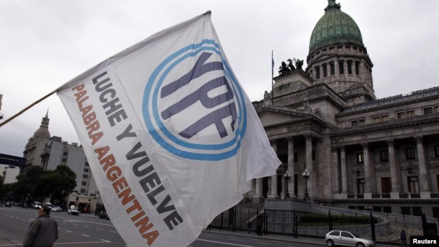 Un hombre agita una bandera con el logo de YPF en frente del congreso argentino, en Buenos Aires, donde esta maduraga de jueves fue aprobado el decreto de expropiación de YPF.