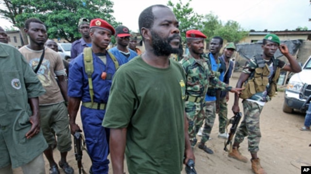 A man known as Commander Bauer, the chief of a group that calls itself the 'invisible commandos' and backs Alassane Ouattara, walks with his fighters in northern Abidjan's Abobo district, March 26, 2011