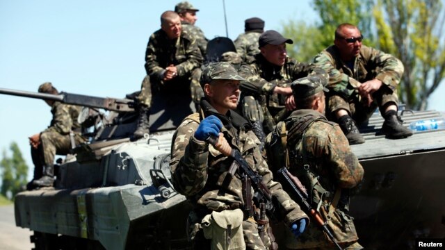Ukrainian soldiers stand guard beside an armored personnel carrier at a checkpoint in Mariupol, eastern Ukraine, May 7, 2014.