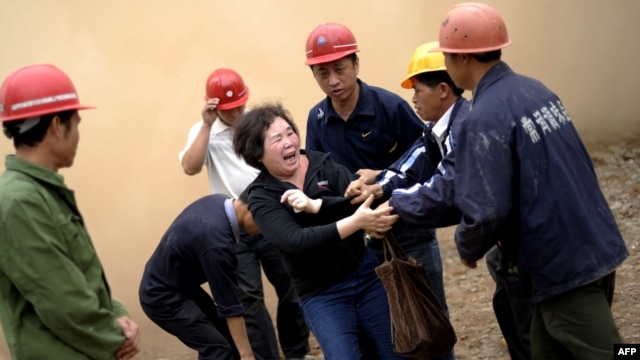 Huang Sufang (C) attempts to protect her home as workers move in for demolition orders in Yangji village, Guangzhou, south China's Guangdong province on March 21, 2012. 