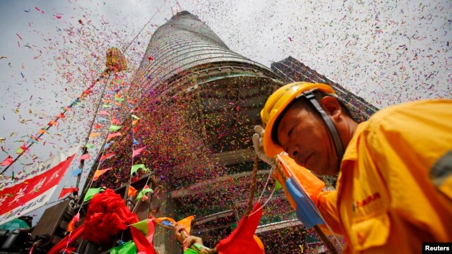 随着最后一根钢梁星期六被起重机送上632米高的“上海中心”楼顶，工人参加庆祝仪式  